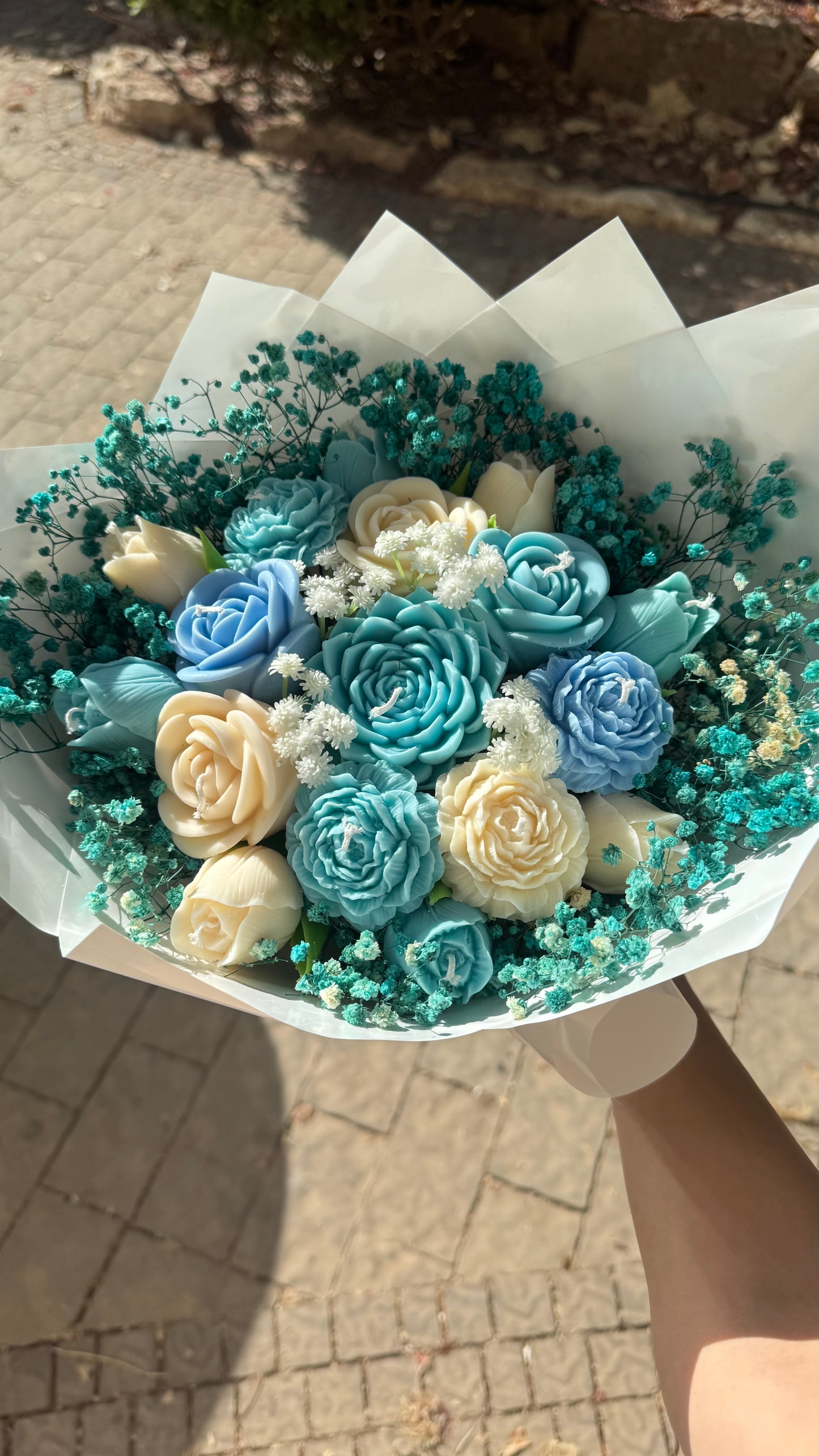 Bouquet of blue and white flowers in a paper wrap held by a person.
