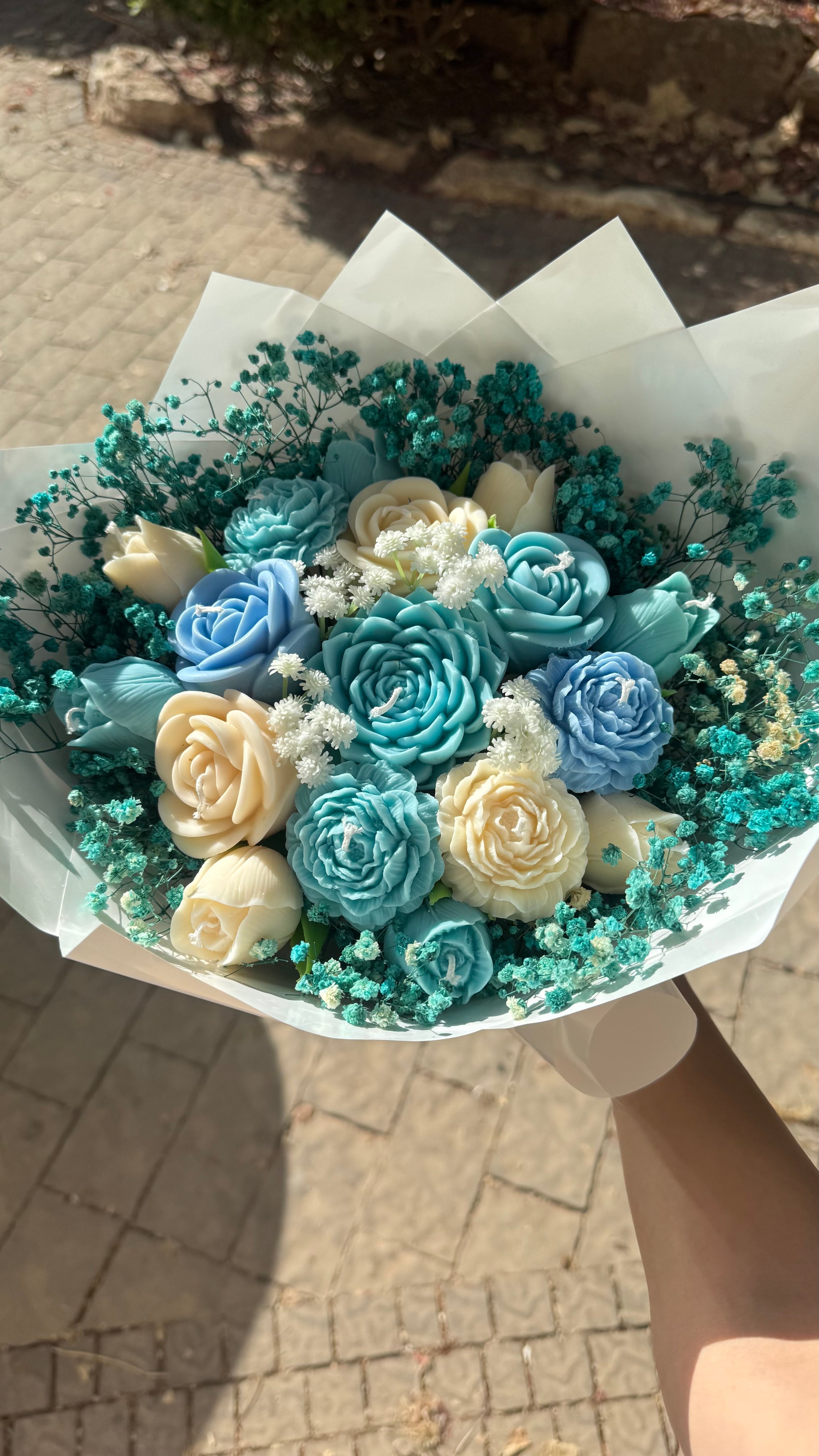 Bouquet of blue and white flowers in a paper wrap held by a person.